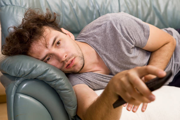 istock Lazy man with the remote on the couch 1036832752
