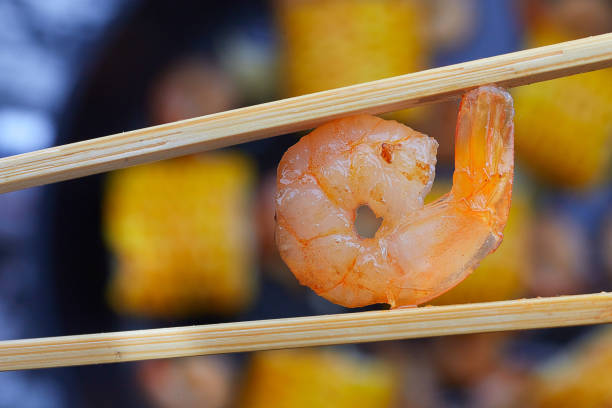 Fried shrimp between chopsticks. The concept of East Asian food.