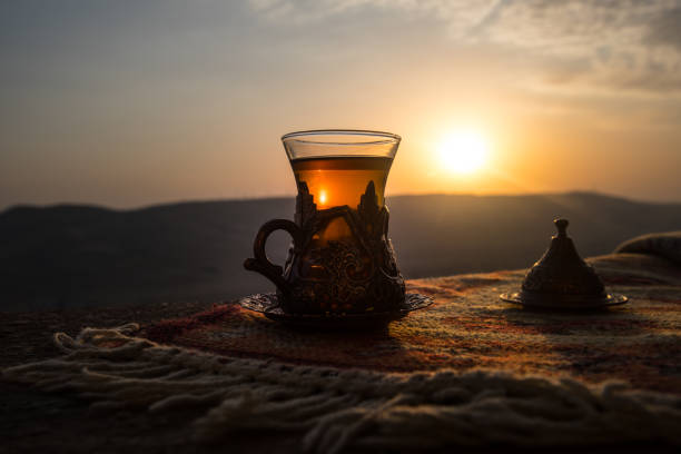 istock Arabian tea in glass on a eastern carpet. Eastern tea concept. Armudu traditional cup. Sunset background. Selective focus 1036863394