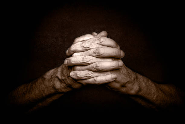 Man's Hands with crossed fingers. This is a classical gesture of a person praying God in the christian religions.