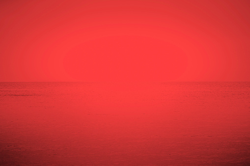Vivid abstract red seascape. Serene atmospheric sky and ocean nature background.  Copy space; toned image; soft texture; wallpaper.