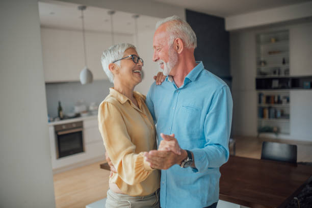 Couple dancing at home Romantic couple dancing at home and smiling while doing so middle aged couple dancing stock pictures, royalty-free photos & images