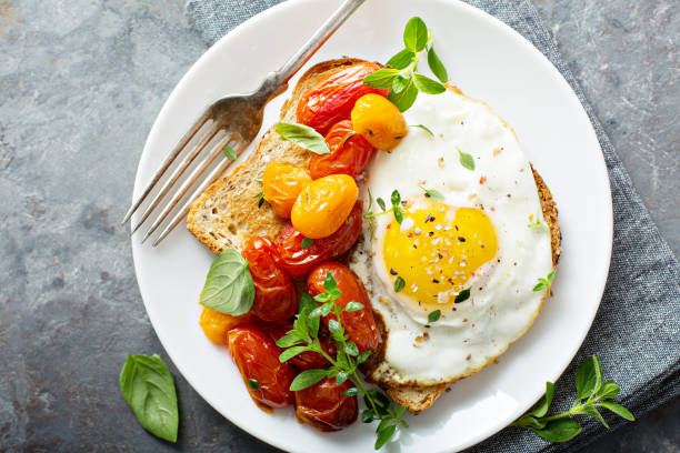 multigrain toast with fried egg and roasted tomatoes - breakfast plate imagens e fotografias de stock