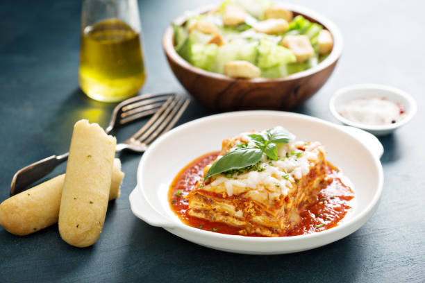 Traditional lasagna on white plate Traditional lasagna on white plate with caesar salad and breadsticks breadstick stock pictures, royalty-free photos & images