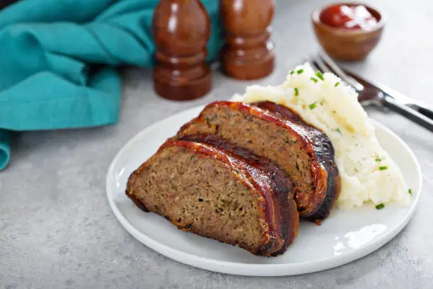Meatloaf wrapped in bacon with mashed potatoes