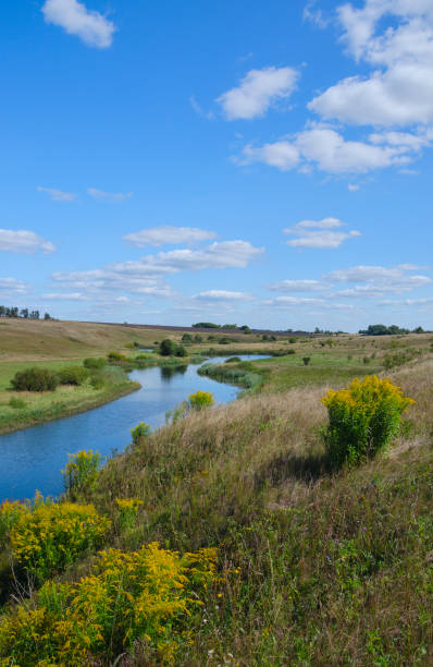 istock Sunny summer landscape with river,fields,green hills and beautiful clouds in blue sky. 1036892432