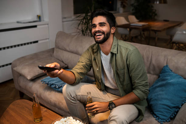 istock A young man sitting on the couch and watching TV 1036892672