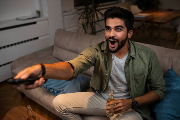 istock A young man sitting on the couch and watching TV 1036892828