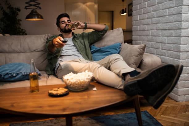 Young man lying on couch watching TV stock photo