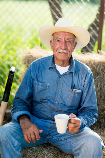 istock Senior mexican man sitting on haystack and holding cup 1036920150
