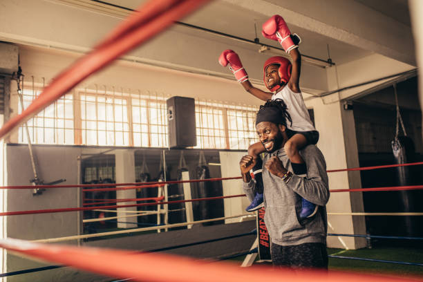 istock Happy boxer kid and coach celebrating victory standing inside boxing ring 1036920930