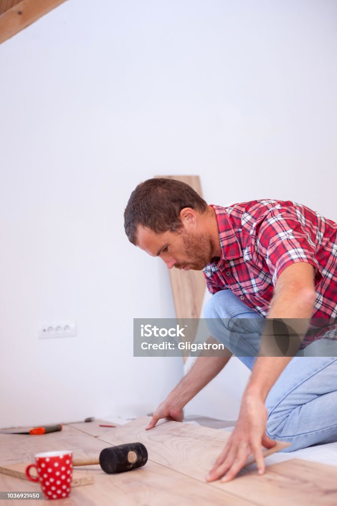 Young man installing laminate flooring in new apartment or house Young man installing laminate flooring in new apartment or house. Home improvement and renovation concept 30-39 Years Stock Photo