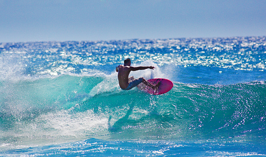 A local Hawaiian surfer surfing at Poipu Beach, Kauai, Hawaii.