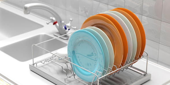 Dish drying rack with colorful clean plates on a white kitchen sink counter. 3d illustration