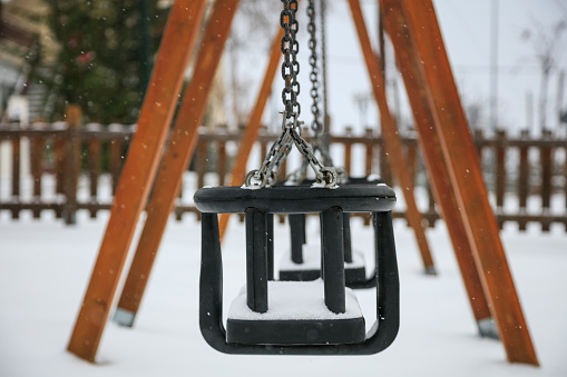 Wooden swing covered with snow