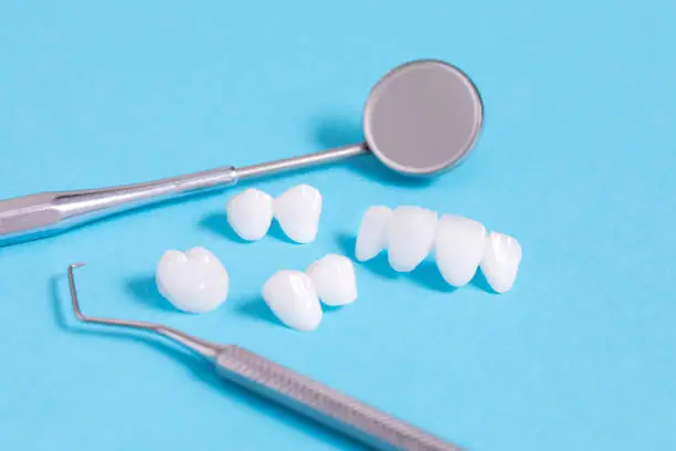 Photo of Zircon dentures samples with dental tools - Ceramic veneers - lumineers