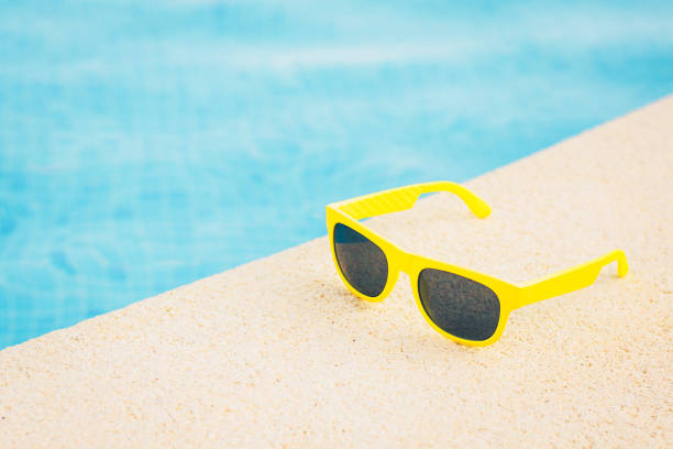 amarillo gafas de sol cerca de la piscina azul - table chair white curve fotografías e imágenes de stock