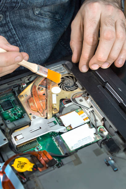 istock The serviceman cleans the dust from his laptop with a brush. 1036966714