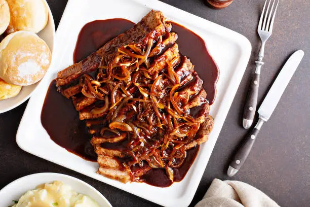 Sliced brisket on a plate with caramelized onions