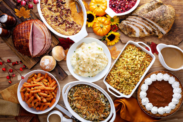 Thanksgiving table with turkey and sides Thanksgiving table with roasted turkey, sliced ham and side dishes food table stock pictures, royalty-free photos & images