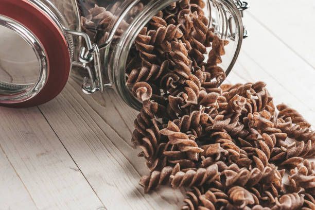 istock Tilted glass jar with pasta on the table 1036970446