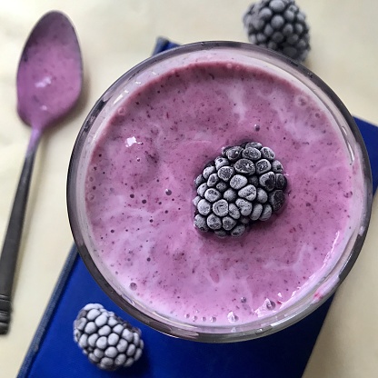 Blackberry smoothie on book with frozen berries.  iPhone