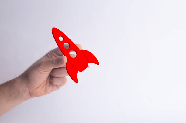 istock Wooden red rocket in hand on a white background. A man is playing with a rocket. Minimalism, space travel and tourism, commercial rocket launches into space. The conquest of other planets. 1036980996
