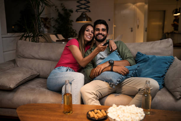 istock Couple sitting on sofa and watching television 1036984294