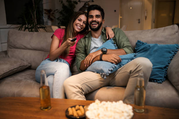 istock Couple sitting on sofa and watching television 1036985616