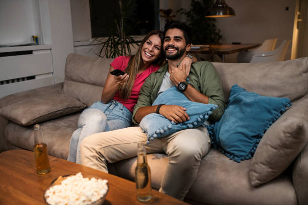 istock Couple sitting on sofa and watching television 1036985656