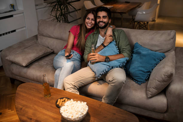 istock Couple sitting on sofa and watching television 1036988748