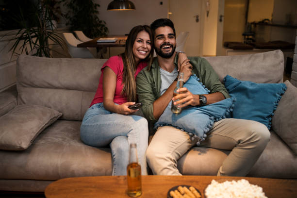 istock Couple sitting on sofa and watching television 1036988882