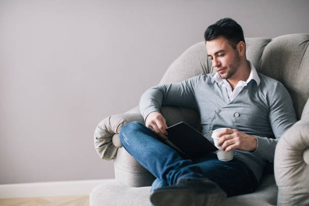 istock Handsome man sitting in an armchair and reading 1036988916
