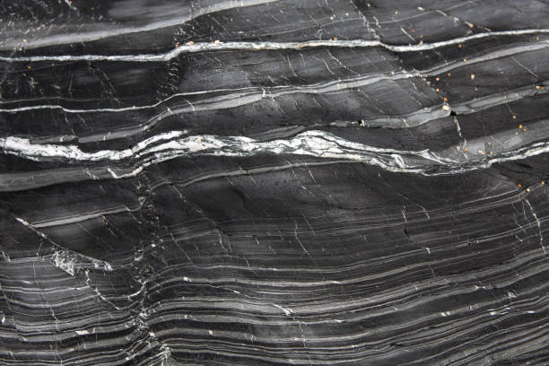 Layers of textured slate and marble A geology background of layers of grey slate and marble compacted together in a cross section of a cliff side with copy space extreme terrain stock pictures, royalty-free photos & images