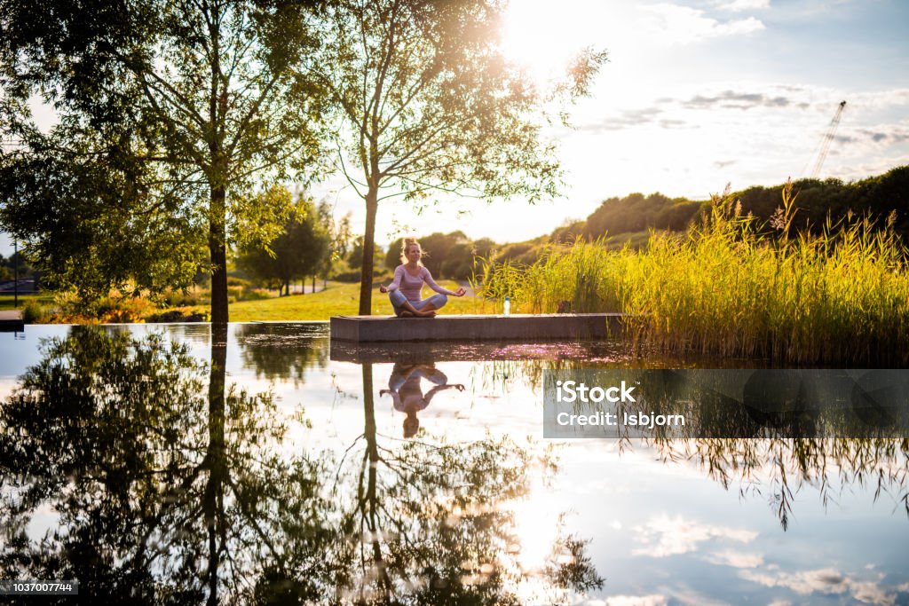 Outdoor meditation. Young beautiful woman exercising yoga in park at sunset. Human Brain Stock Photo