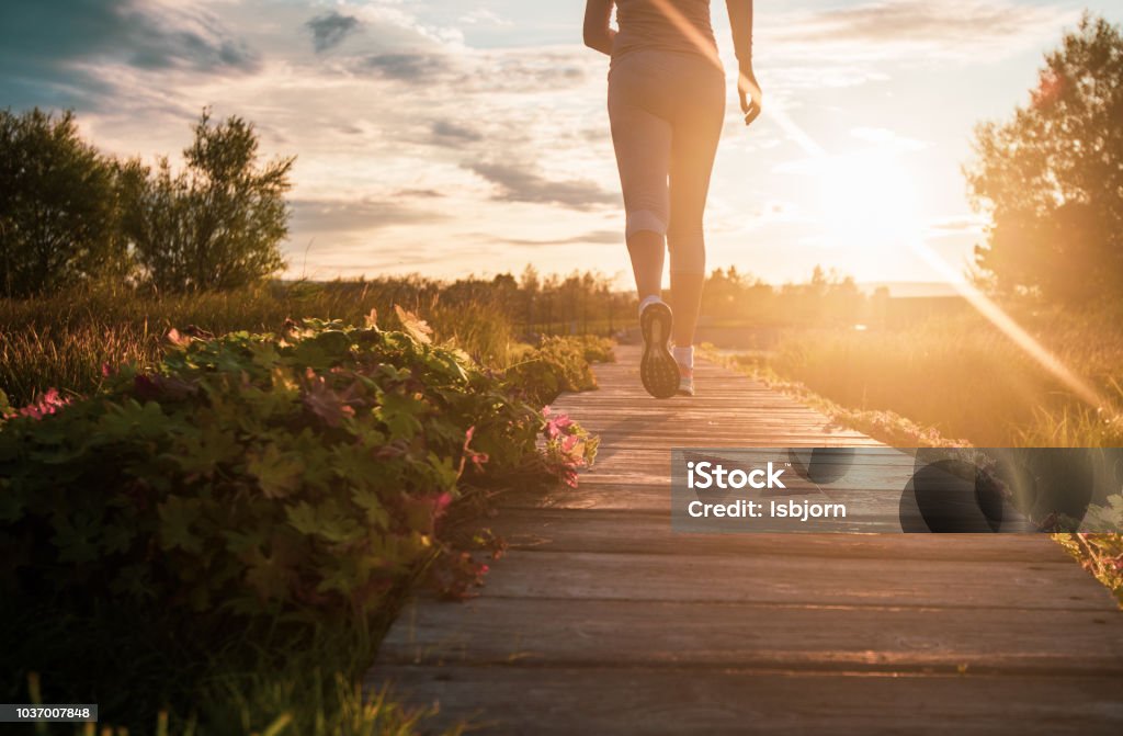 Close up of jogging. Close up of unknown woman running in park at sunset. Wellbeing Stock Photo