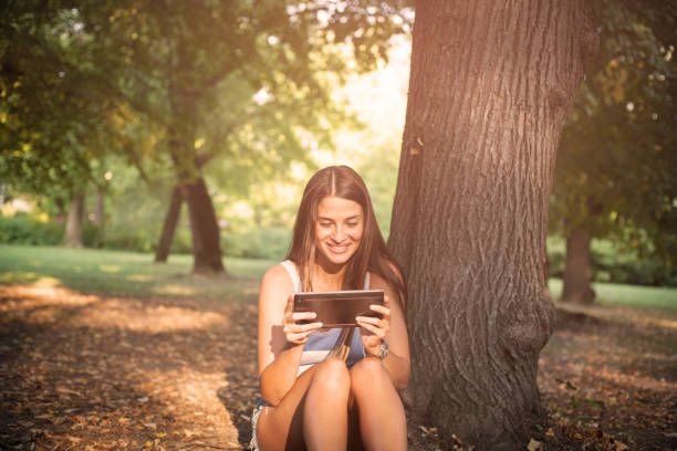 istock Happy young woman using digital tablet in park . 1037008026