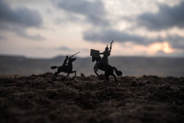 istock Medieval battle scene with cavalry and infantry. Silhouettes of figures as separate objects, fight between warriors on sunset foggy background. 1037014122