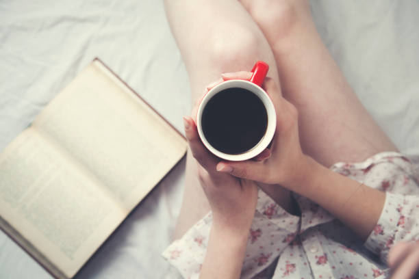 istock woman hand  cup of coffee and book 1037036700