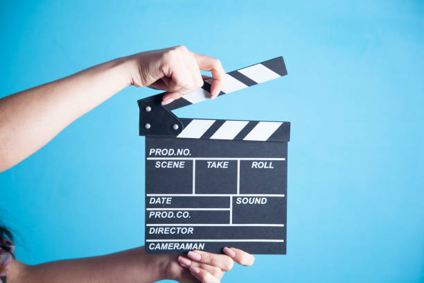 istock woman hands holding film clapper isolated on blue background 1037036742