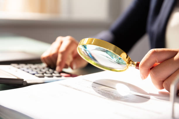 istock Businesswoman Examining Invoice Through Magnifying Glass 1037076730