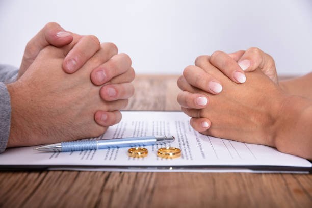 couple's hand with divorce agreement and wedding rings - divórcio imagens e fotografias de stock