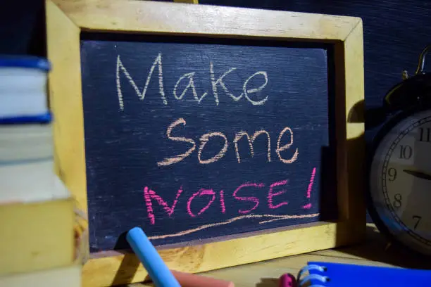 Photo of Make some noise! on phrase colorful handwritten on blackboard.