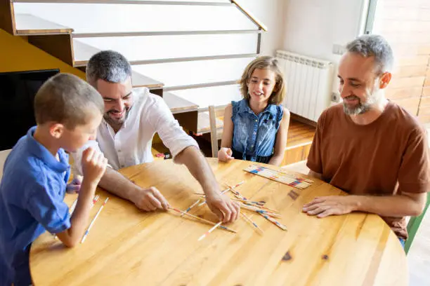 Gay parents playing Pick Up Sticks with their kids