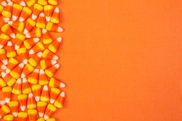 Halloween Candy Corn Background on an Orange Surface Halloween Candy Background on an Orange Surface candy corn stock pictures, royalty-free photos & images