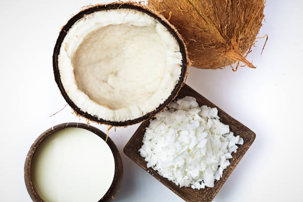 Coconut, coconut Cream Milk and Coconut flakes Studio Still Life Studio still life of a whole coconut and and halved opened coconut with a bowl of coconut cream and milk and coconut flakes. coconut milk photos stock pictures, royalty-free photos & images