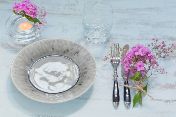 istock Rustic table setting with pink flowers, empty glass and candle on light wooden table. 1037162976