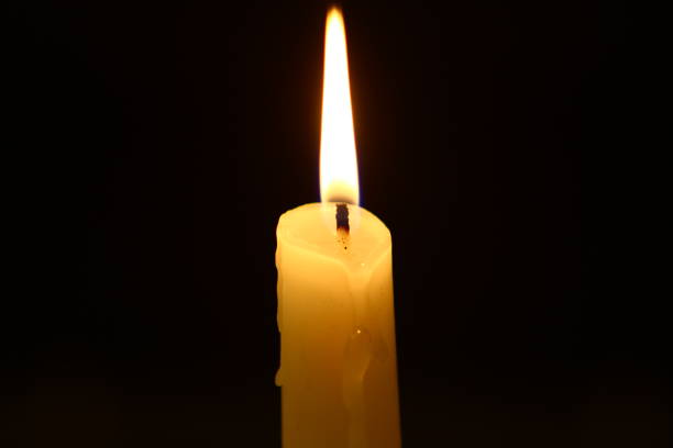 istock nice paraffin flaming candle with small fire on heavy black background. 1037163816