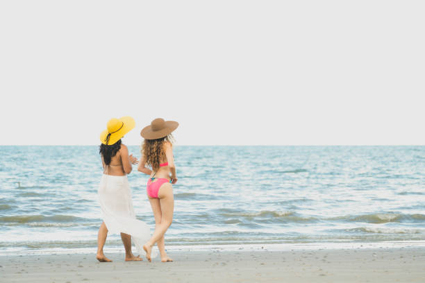 istock Happy women go sunbathing at sand beach in summer. 1037179440