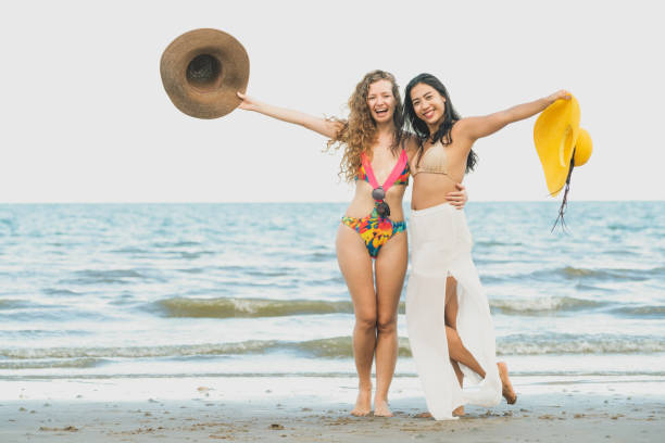 Happy women dance on sand beach in summer.